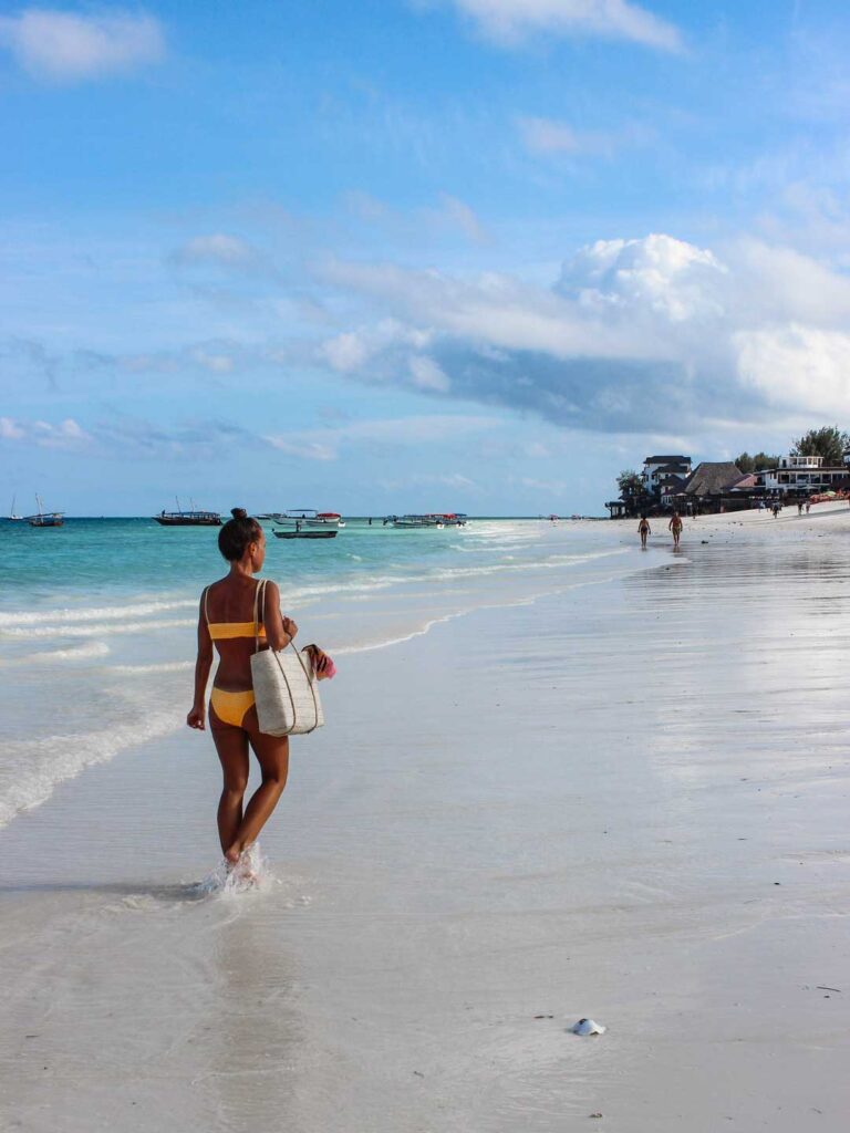 a female walking up the shoreline of a beautiful beach in Zanzibar
