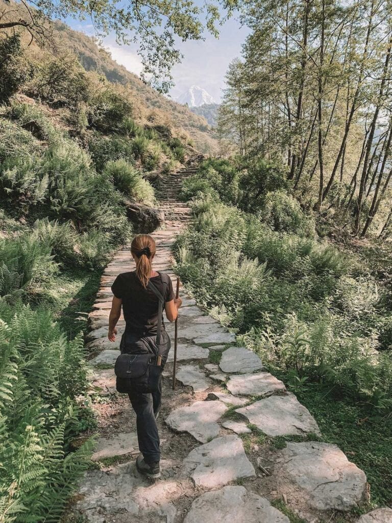 Lady walking along a stone path towards mountain view in Nepal