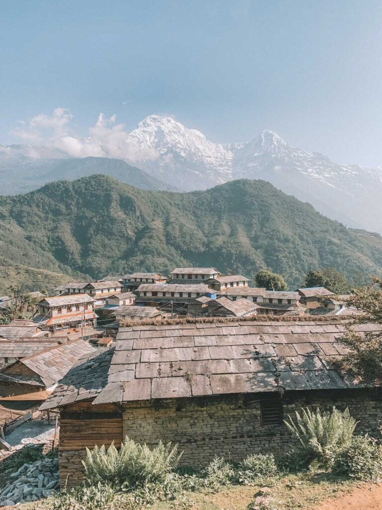 Trek Annapurna Base Camp. View of Nepalese village, wooden houses with snow covered mountains in the background