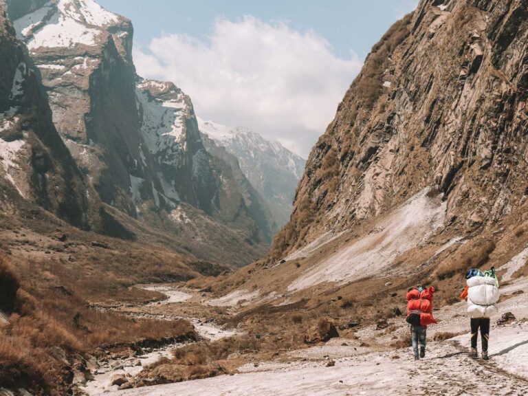 two porters are trekking while carrying luggage in the Annapurna sanctuary