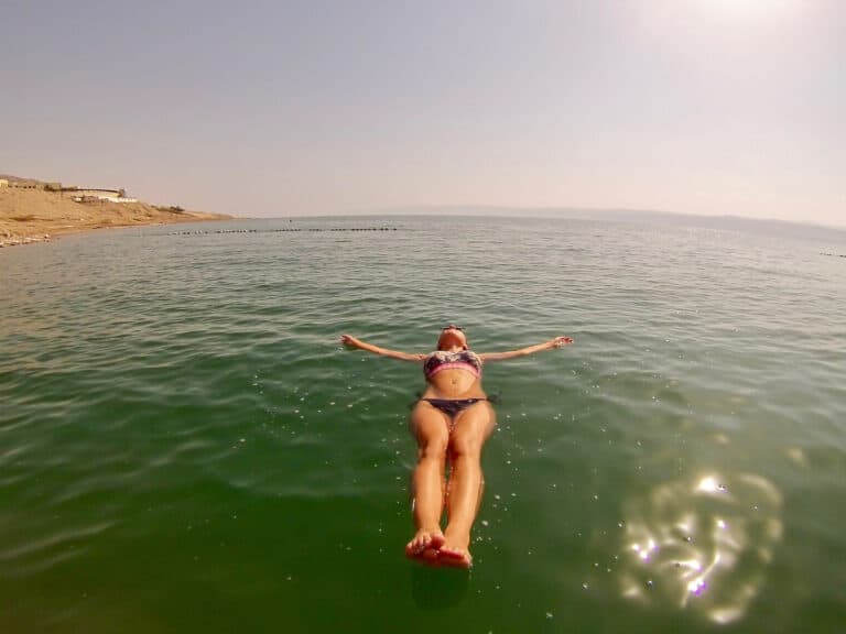 A female lays floating in the water with her arms out while she travels in Jordan