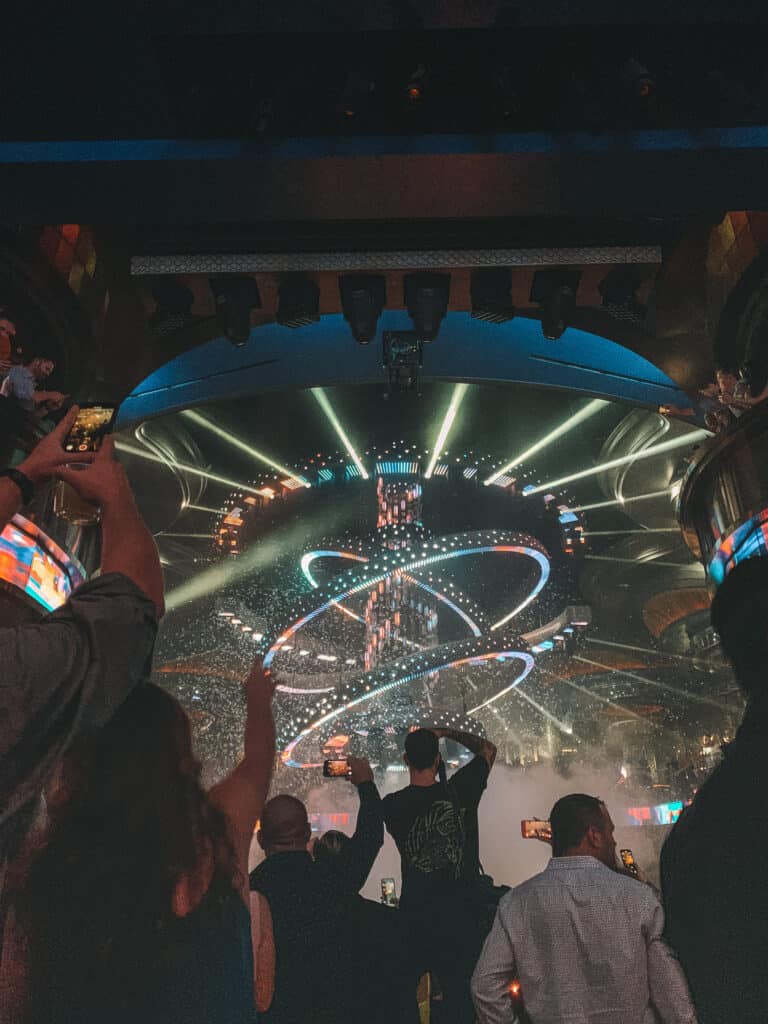 Standing behind a crowd of people in Omnia Nightclub, the centre of the room has many shining colorful lights
