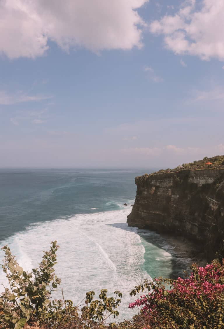 standing at Uluwatu Temple while traveling in Bali, looking out to the ocean with a large cliff in the background