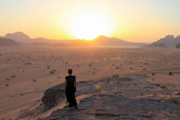 A female stands looking towards the sunset in the desert of Jordan