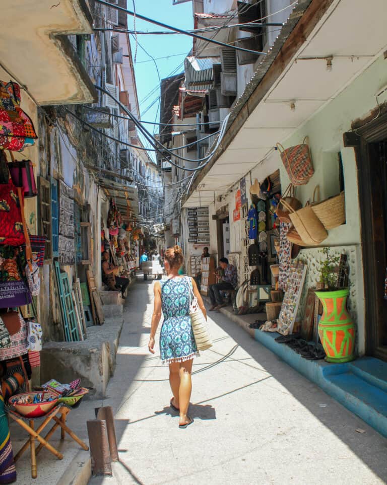 Me walking a street of Stone Town. The street is lined with shops selling craft products