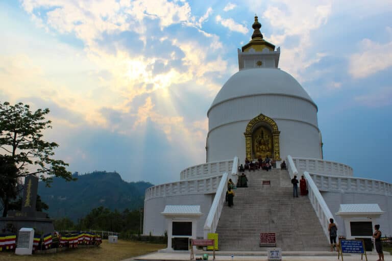 a large white stupa, with a gold roof and gold Buddha
