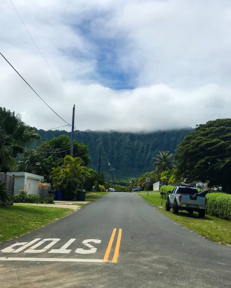 an empty road in Hawaii. it's a cloudy day on Oahu and thick clouds are covering the green hills