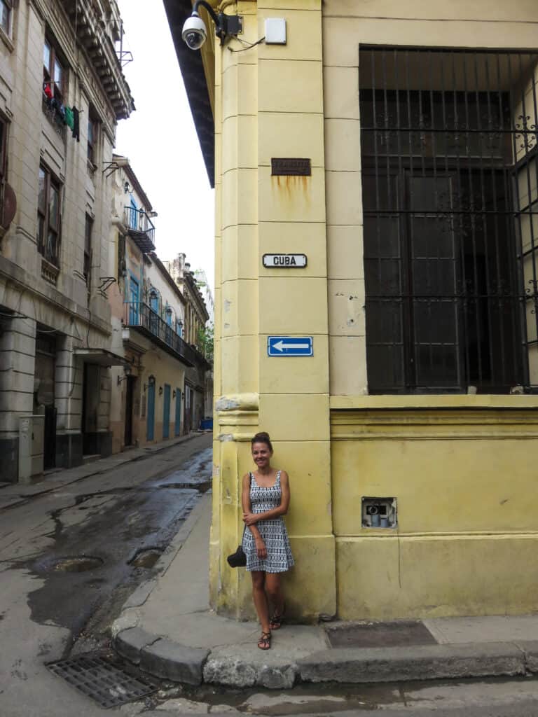 Elyse Stands on the corner in Havana against a yellow wall