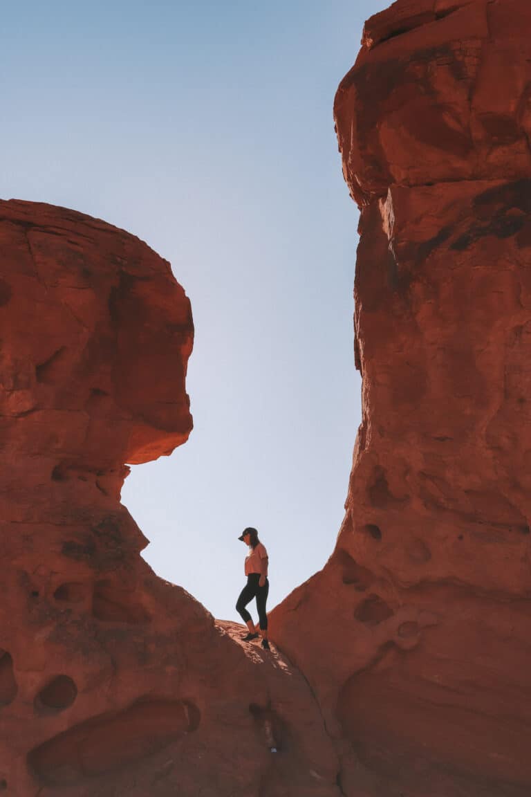 elyse standing up on red sandstone in Valley of Fire, Nevada. The rock formations stand tall either side of her
