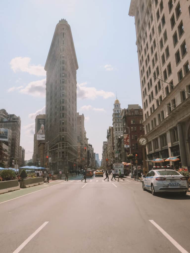 The flat iron building New York City, taken from the middle of the road. Only a few cars are on the road