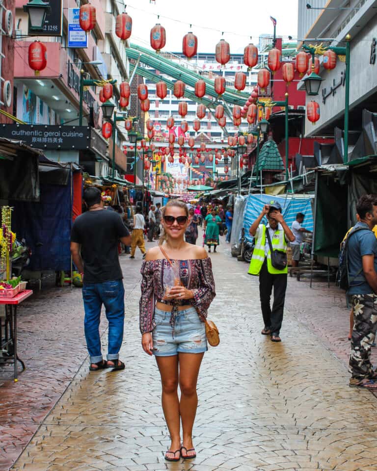 Elyse standing on the road in a quiet market. Red lanterns are hanging across the street