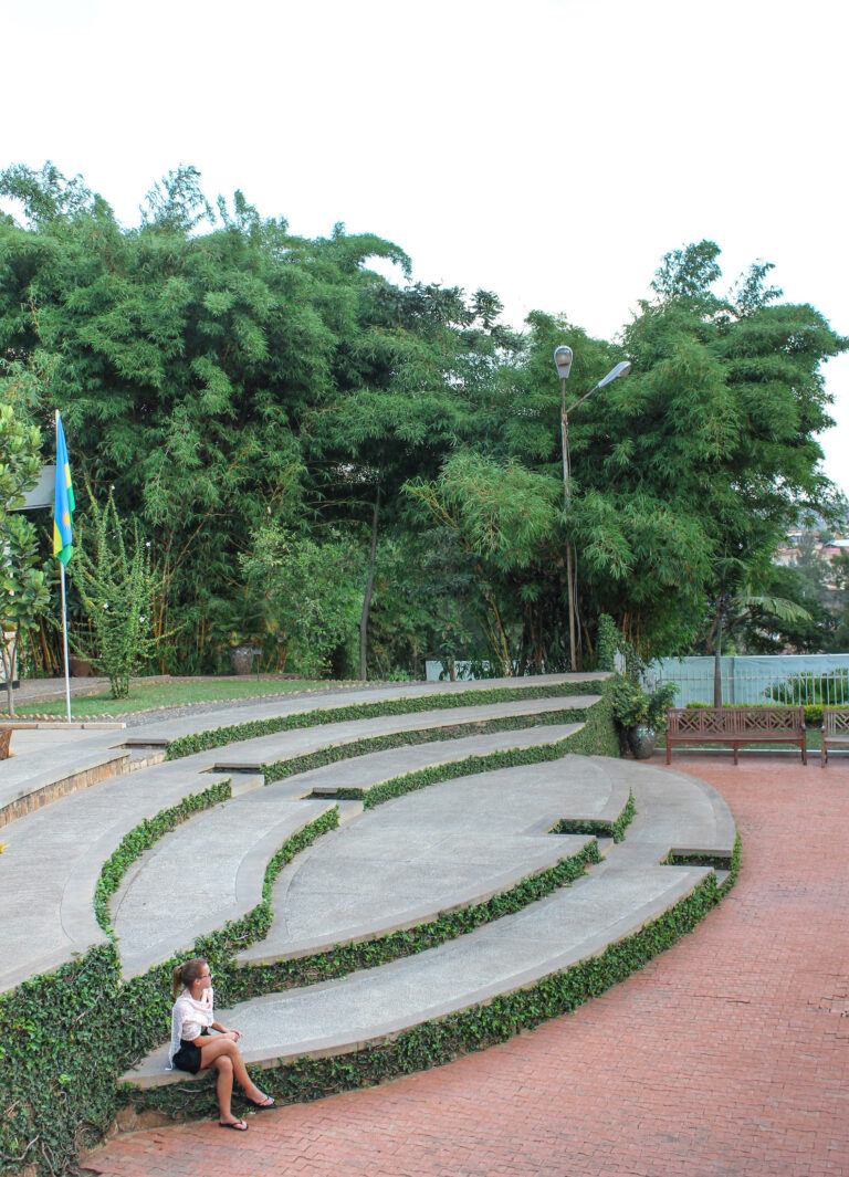 A semi-circle seating area in front of the Kigali Genocide Memorial, Elyse is sitting on one of the lower seats.