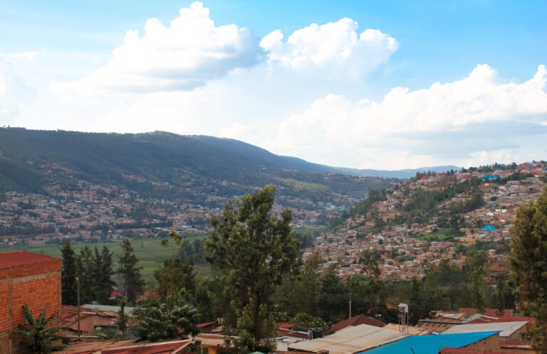 A view of the rolling hills in Rwanda from Kigali city. The hills are filled with peoples homes and it’s a sunny day.