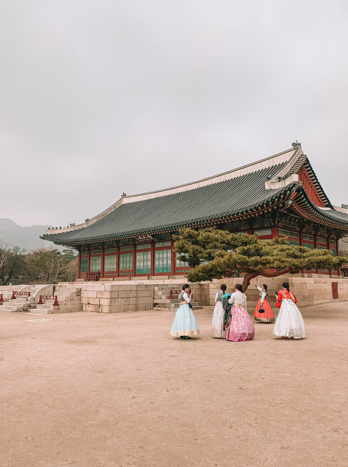 An old Korean palace can be seen behind a tree and 5 girls are posing for photos wearing traditional Korean dress. Here I recap the holidays I had this year