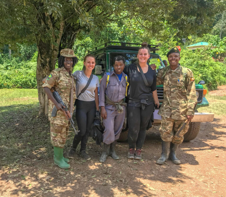 Elyse and Bianca standing with their three African tour guides, a female guide is holding a large riffle.