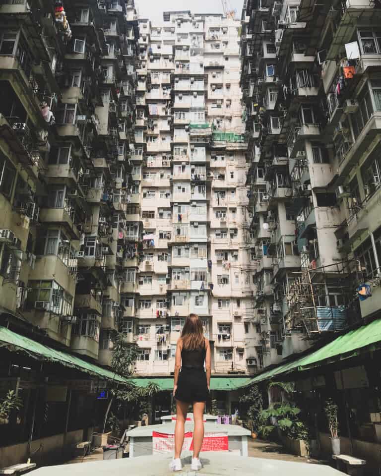 Elyse standing tall looking up at three densely populated apartments buildings