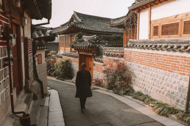 Elyse travels down an empty road between Hanok houses in Seoul