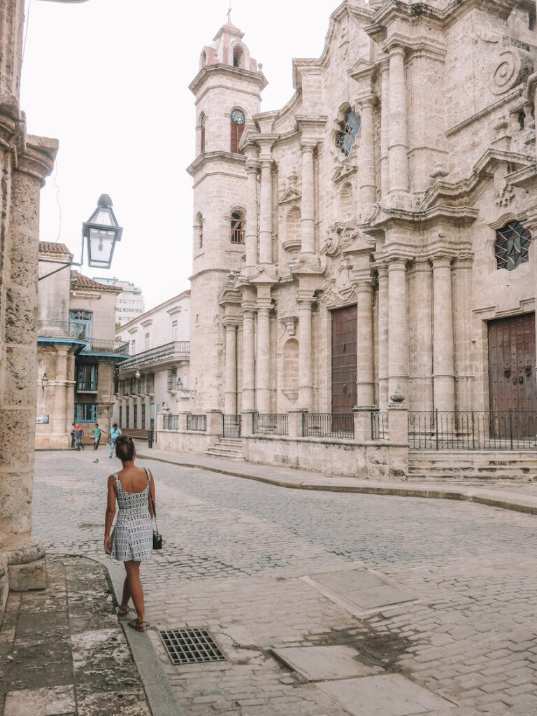 Elyse walking on a quiet footpath, looking at a large church, symbolizing a way to save money when you travel