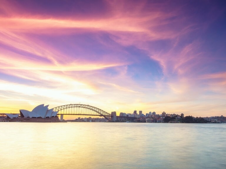 A view of Sydney harbor at sunset. In the image the Sydney opera house and Sydney harbor bridge can be seen. I suggest adding Sydney to your Australian bucket list