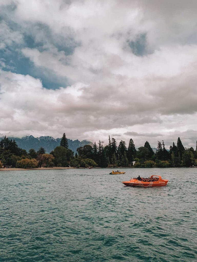 Lake Wakatipu, New Zealand. And orange Jet boat on the calm lake.