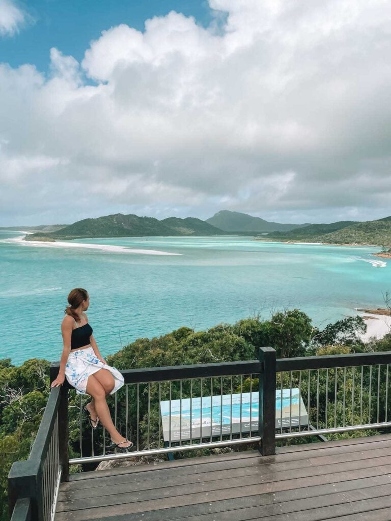 Elyse sitting on the edge of the lookout at Hill Inlet looking out to the swirling sands at Airlie Beach