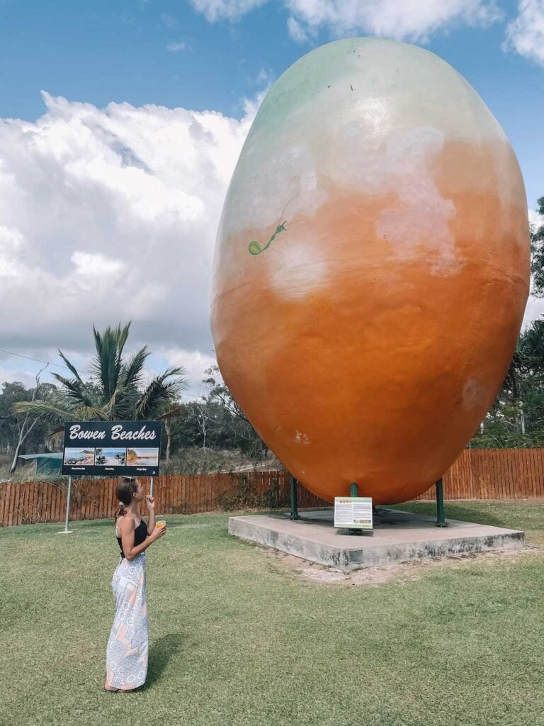 Elyse eating mango sorbet while standing next to the big mango in Bowen QLD