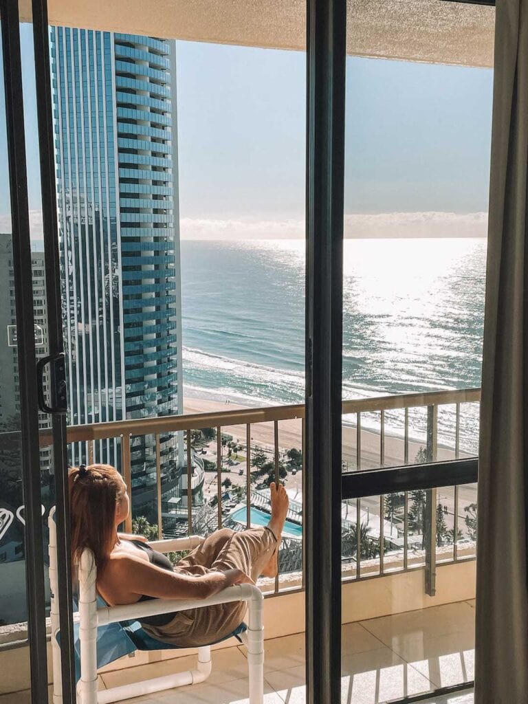 Elyse sitting on a chair on a balcony looking over Surfers Paradise beach