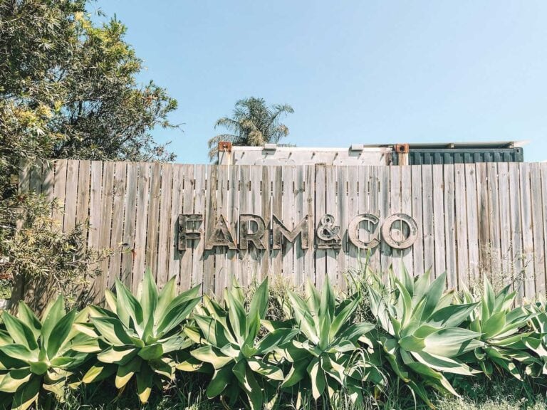 The sign for Farm and Co. The letter are made out of an old metal material and on a wooden fence