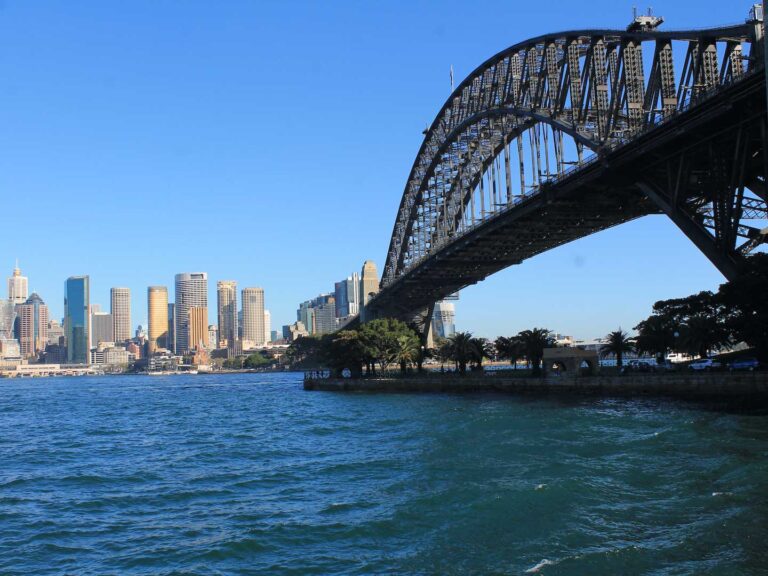 The Sydney Harbour Bridge on a sunny day, there aren't many boats in the water underneath