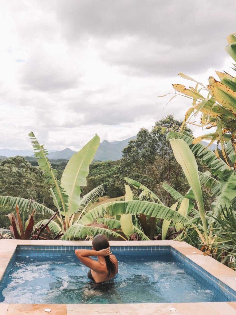 Elyse in the spa at La Rocher Eco Retreat in NSW. The spa is surrounded by tropical trees and it is a very cloudy day