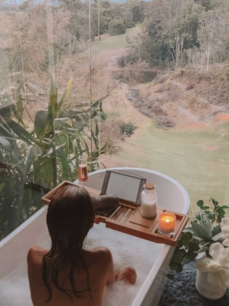 Elyse having a bubble bath with a view of the mountains at an eco friendly retreat in nsw