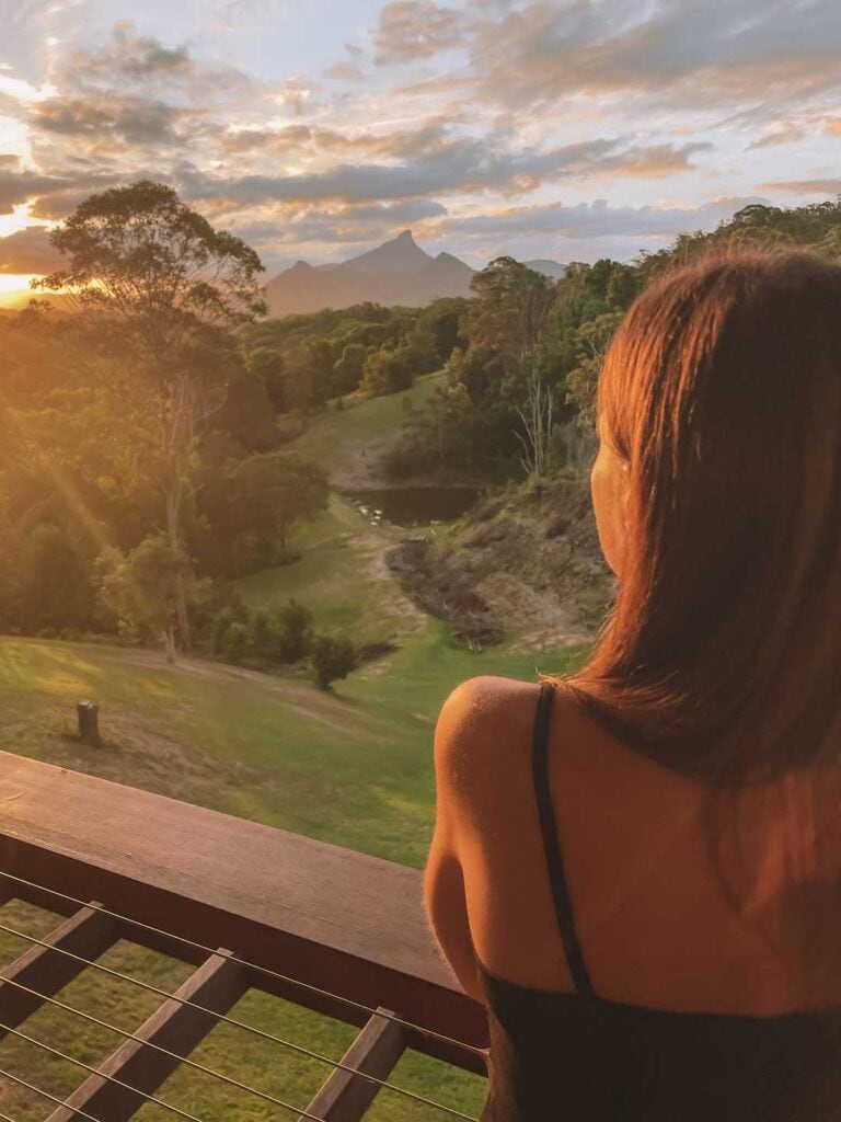 Elyse standing on the balcony at La Rocher Eco Retreat in NSW watching the sunset