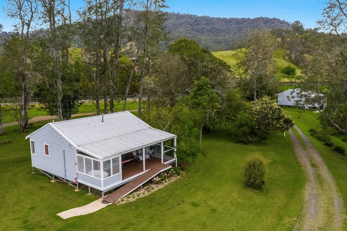 Small white cabin surrounded by greenery