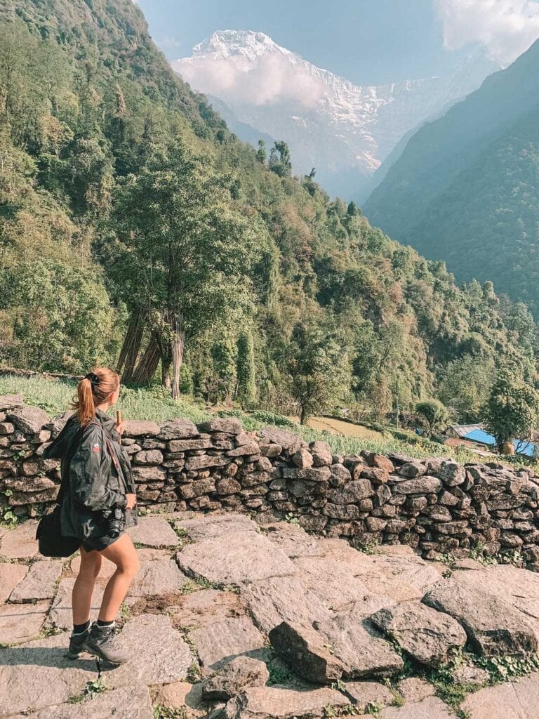 Trekking in Nepal to Annapurna Base Camp, walking along a stone path looking at snowy mountains. After packing for a day hike in Nepal