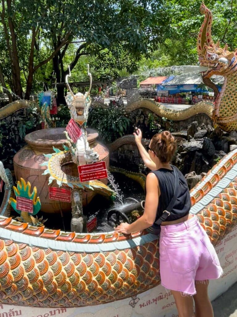Elyse throwing coins in the pond at Wat Samphran