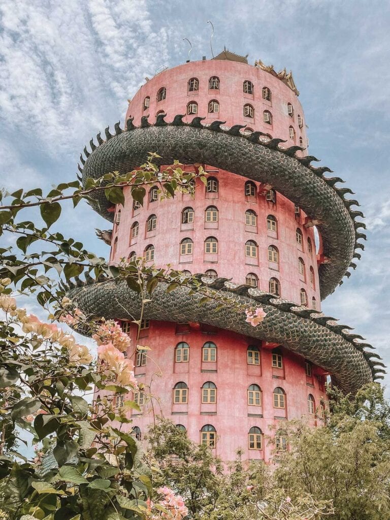 A 17 story pink building with a dragon wrapped around in, located in Thailand