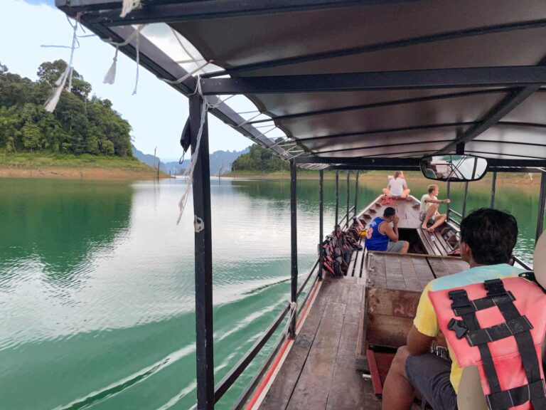 A group of people on a wooden boat, sailing around Khao Sok National park, an activity that's apart of Khao Sok 2 day 1 night tour