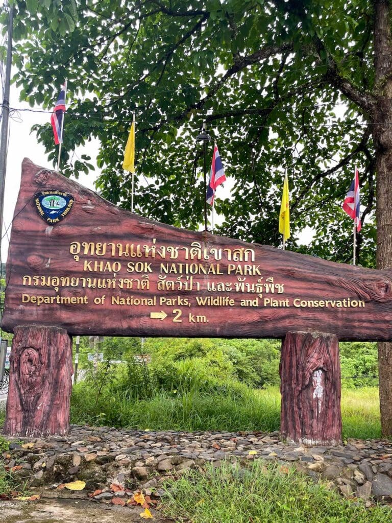 A wooden sign with gold writing advising the beginning of Khao Sok National Park