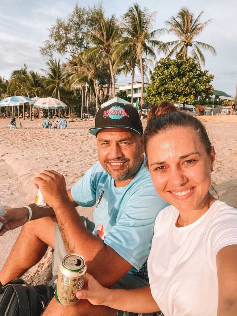 Elyse and Lawrence sitting on Patong Beach, drink local beers