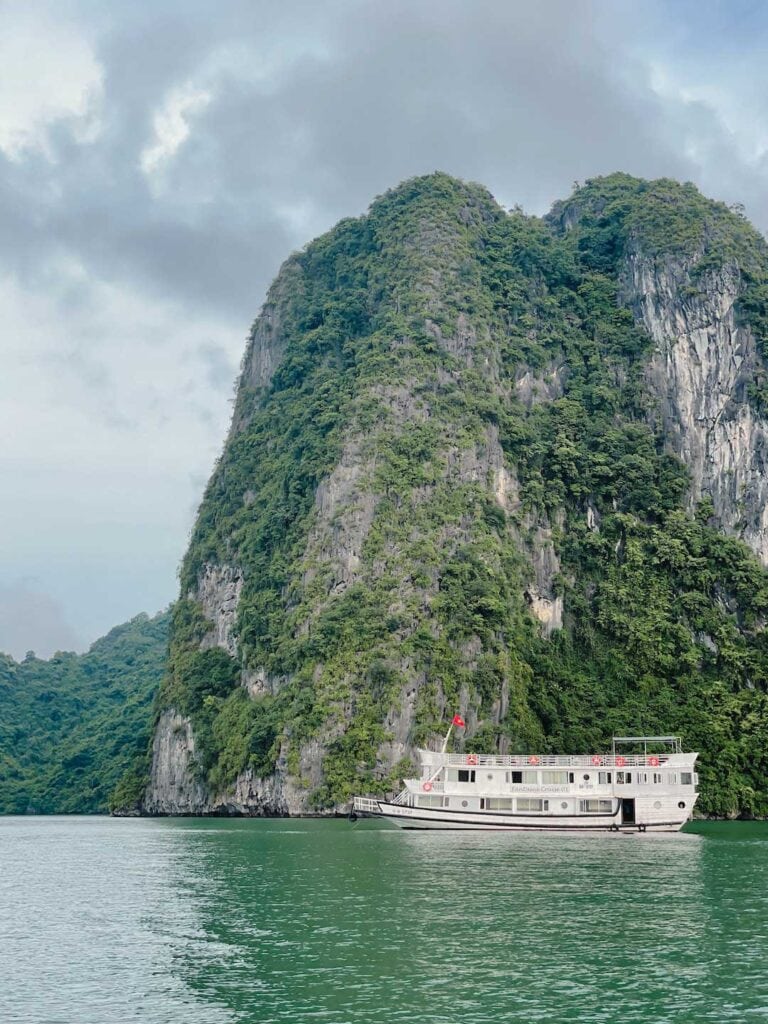 Fantasea cruise boat anchored in Halong Bay next to massive limestone cliffs