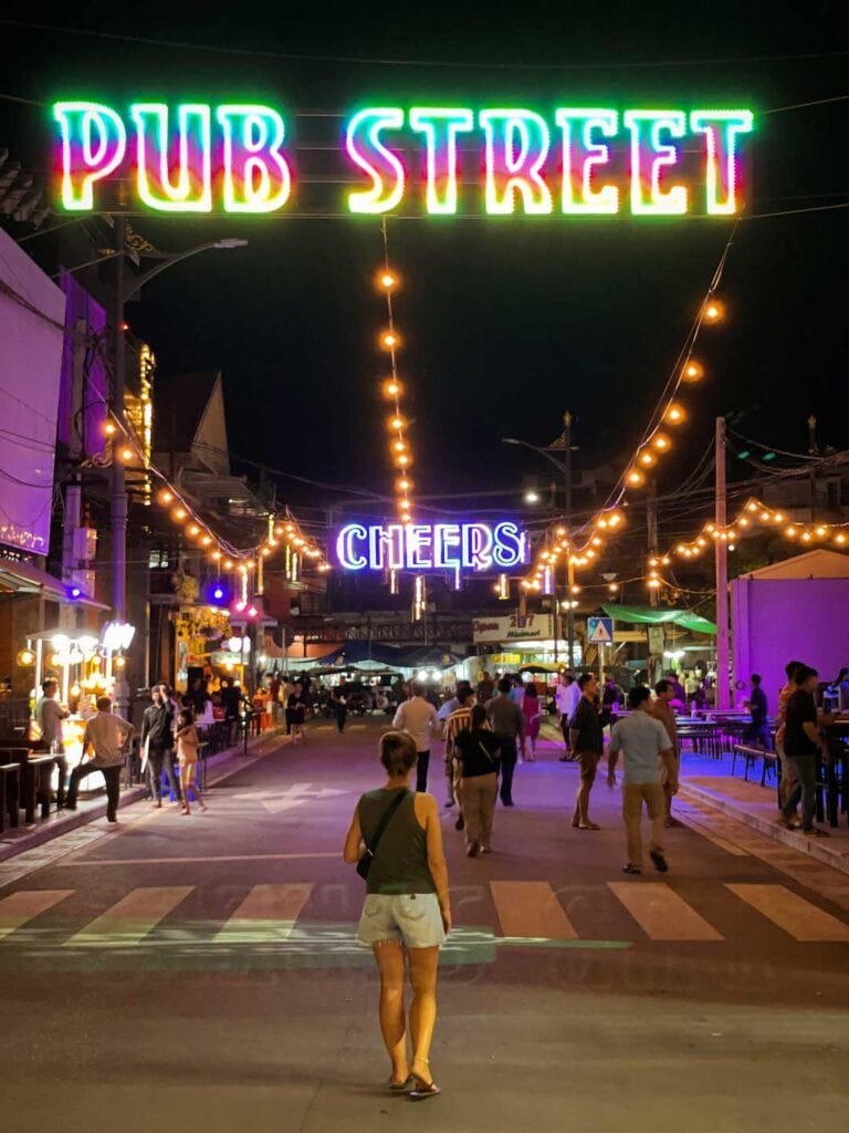 Walk down a quiet Pub Street in Siem Reap. The multicolored neon signs say pub street and cheers