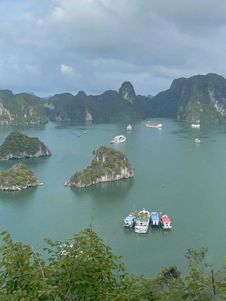 an aerial view of Halong Bay on a cloudy day, with at least 10 boats anchored