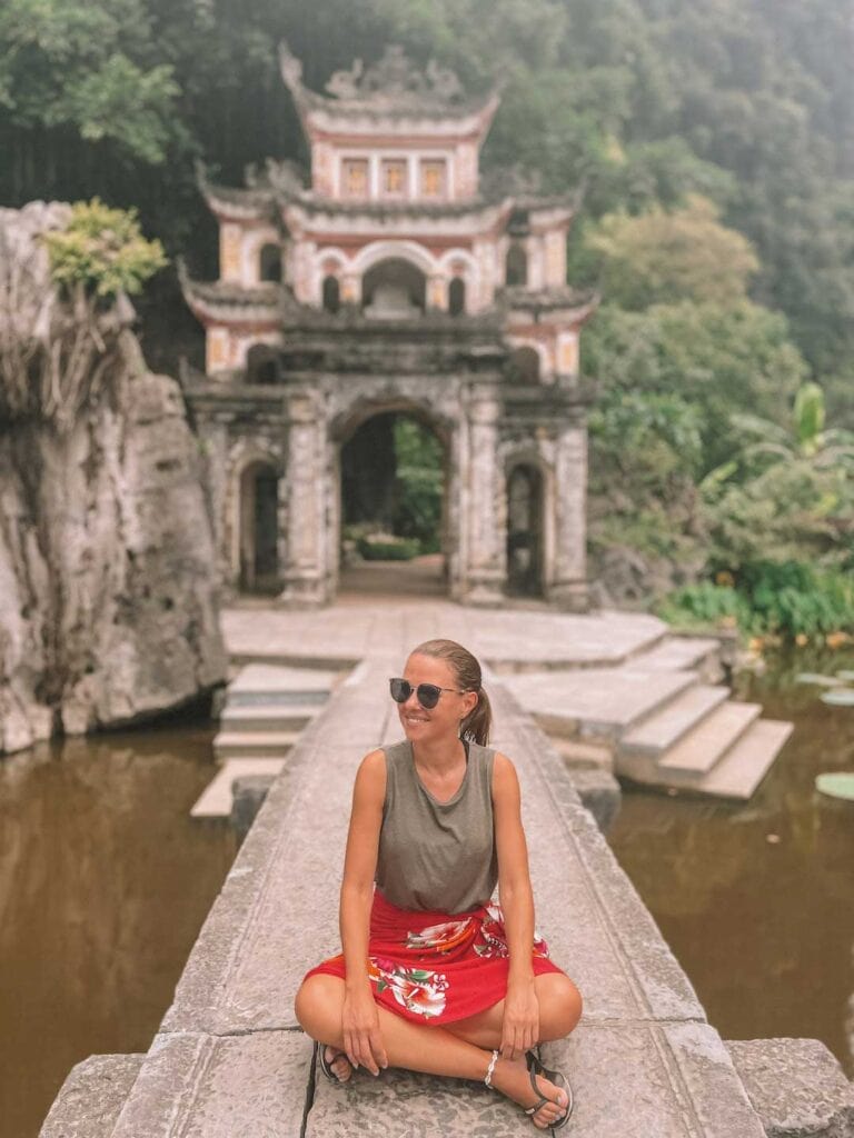 Elyse sitting in front of the Bich Dong Pagoda in ninh binh