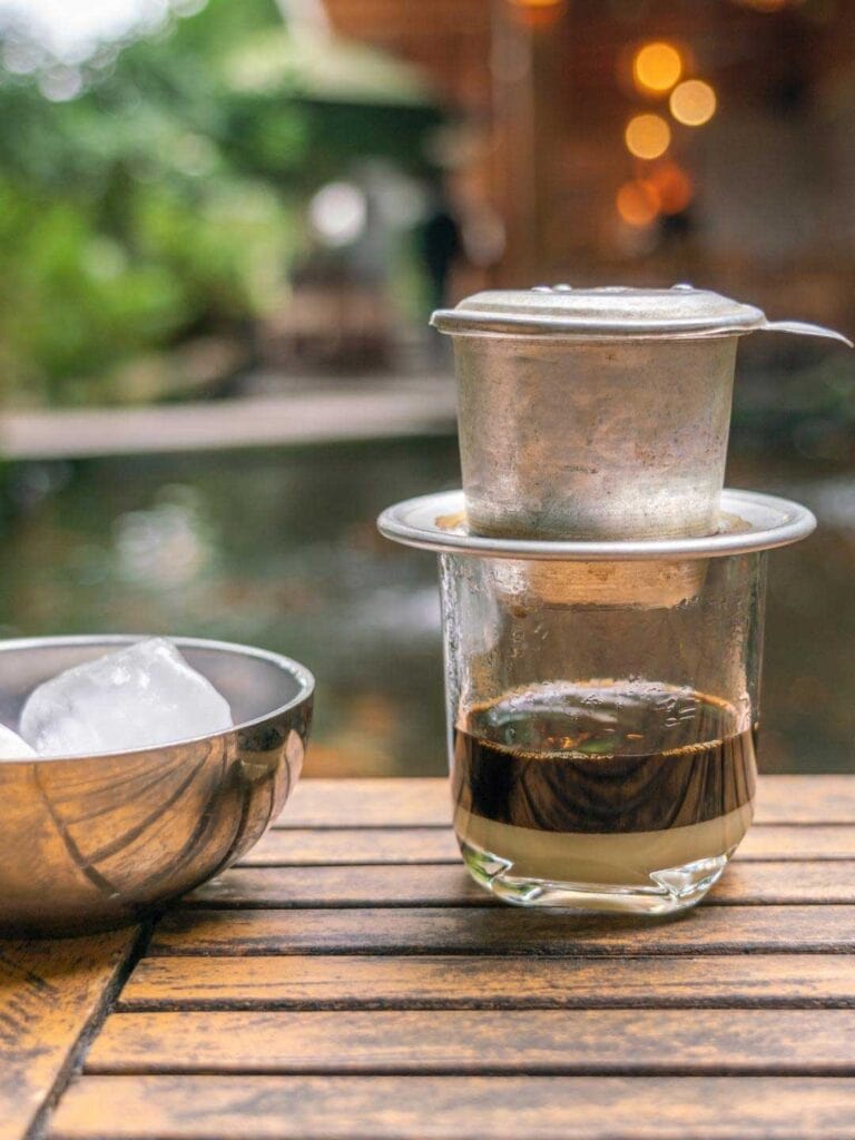 An image of an traditional dip coffee in Vietnam and a bowl of ice cubes next to the coffee