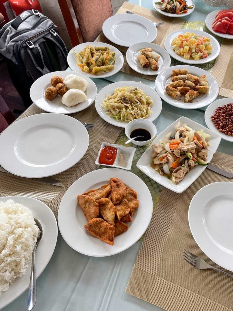 a Table filled with multiple plates of food served on a 1 night cruise on Ha Long Bay