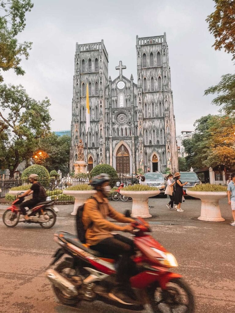 motor bikes and pedestrians passing the St Joseph’s Cathedral in Vietnam