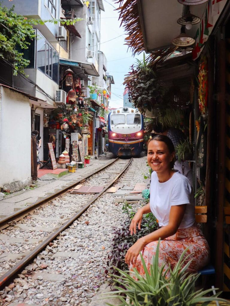 The colorful train passing through train street in Hanoi, traveling very close to the cafes in the side