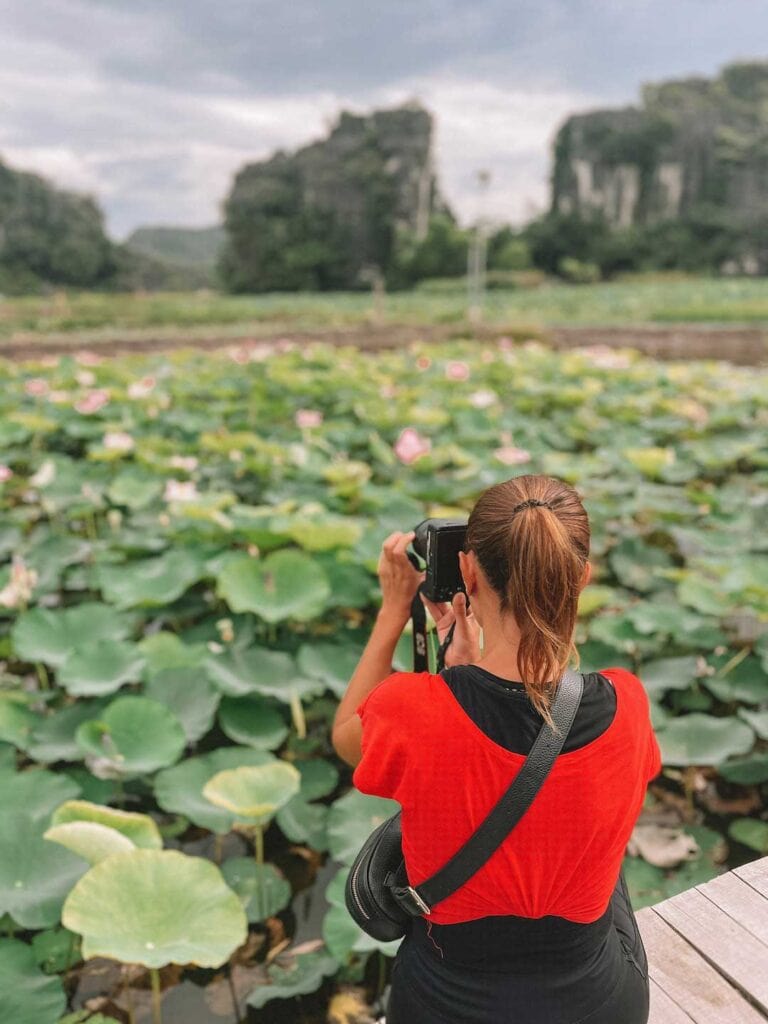 The back of elyse as she takes photos of the lotus pond in Ninh Binh, northern Vietnam