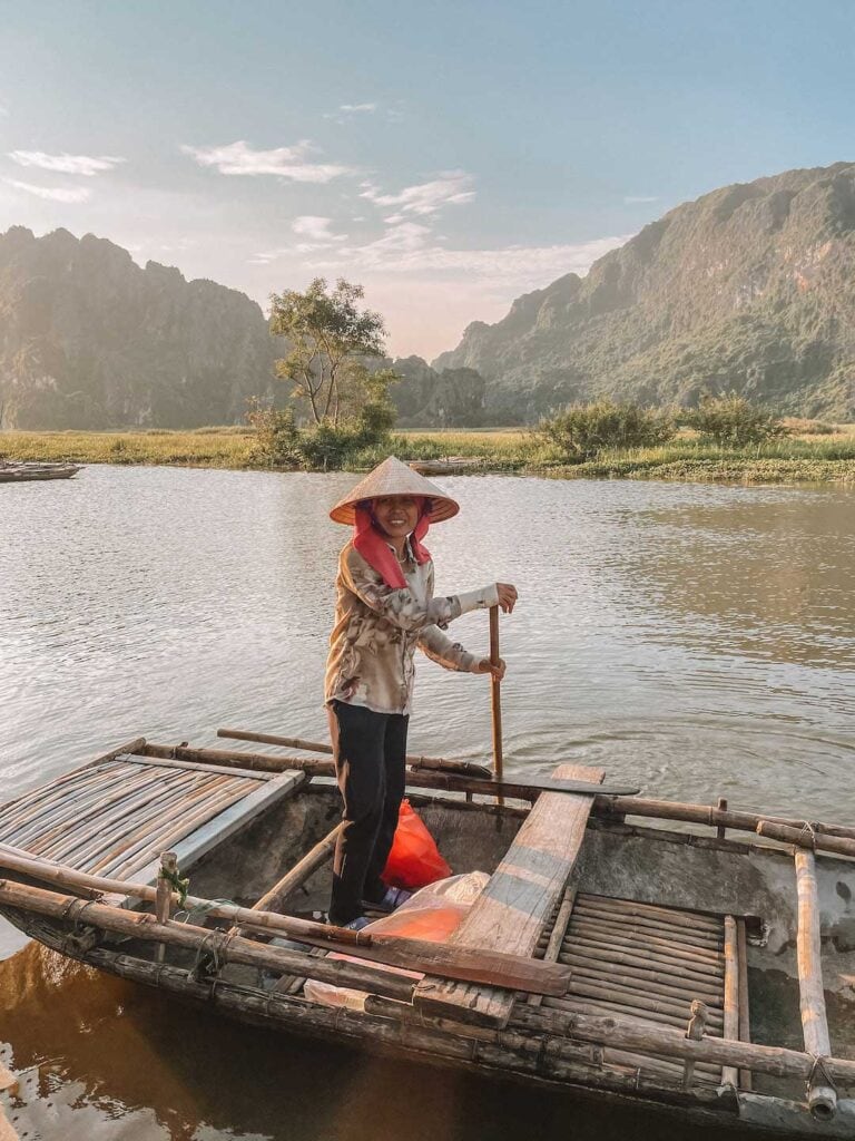 Local Vietnamese woman standing on a bamboo boat in Van Long wetlands nature reserve