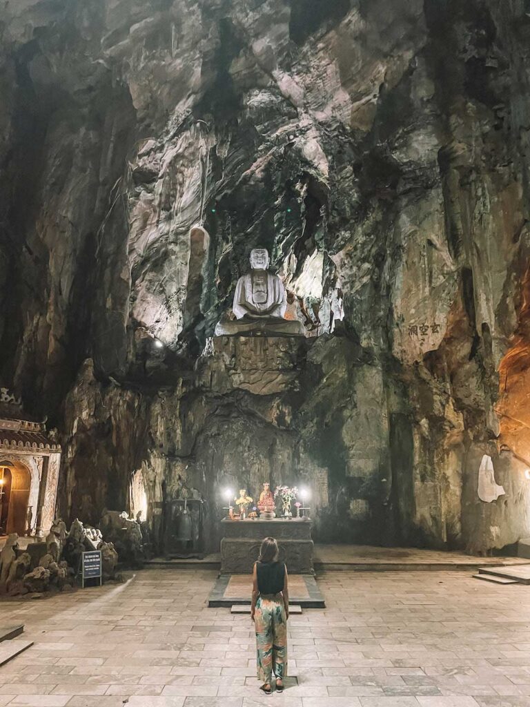Elyse standing inside a cave with Buddhist statues on Marble Mountain